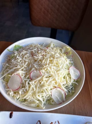 Insalata Due Formaggi topped with shredded cheese and radish slices