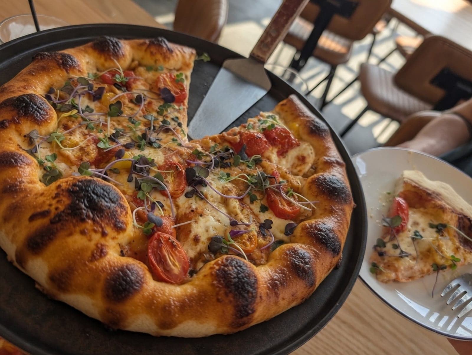 A pizza topped with cherry tomatoes and micro greens at Crust & Cocktails in Akron